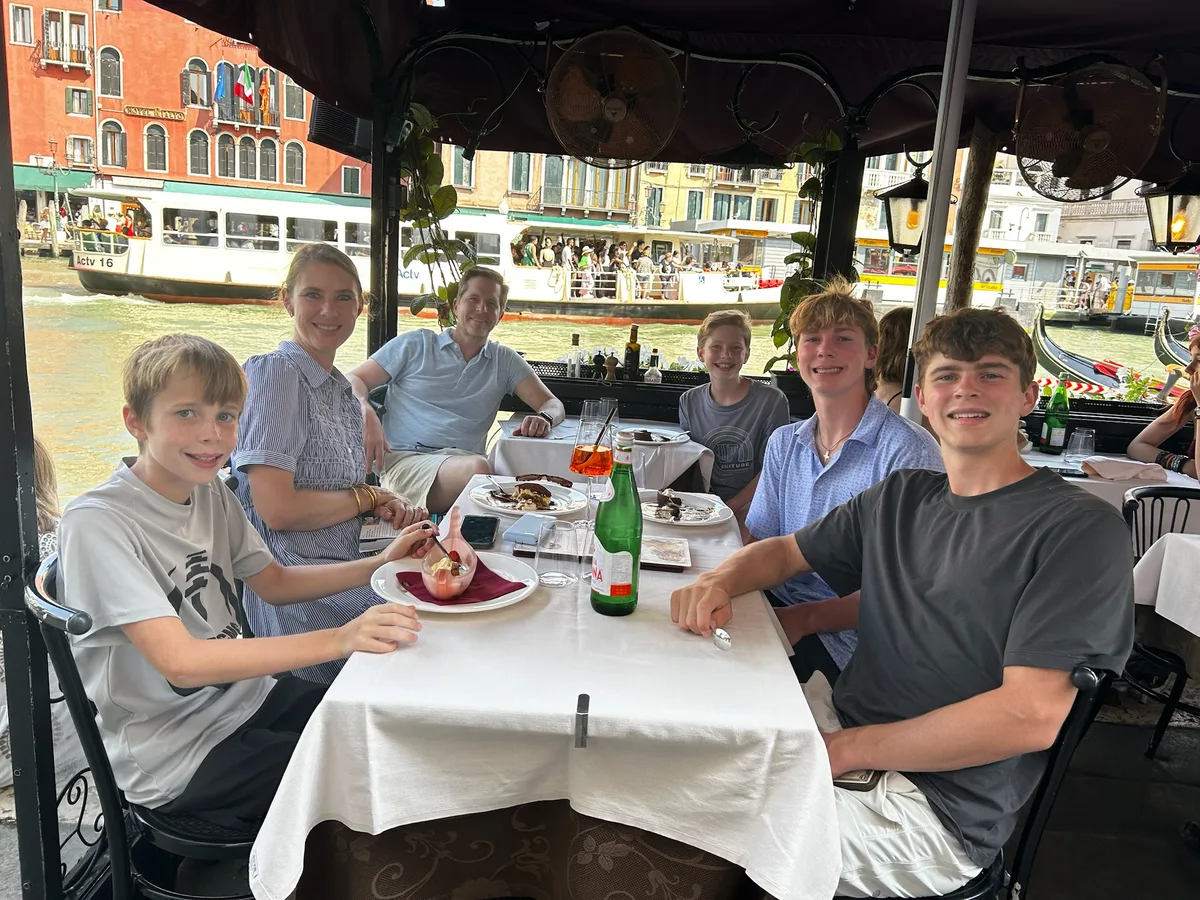 The family eating together at a table beside a canal